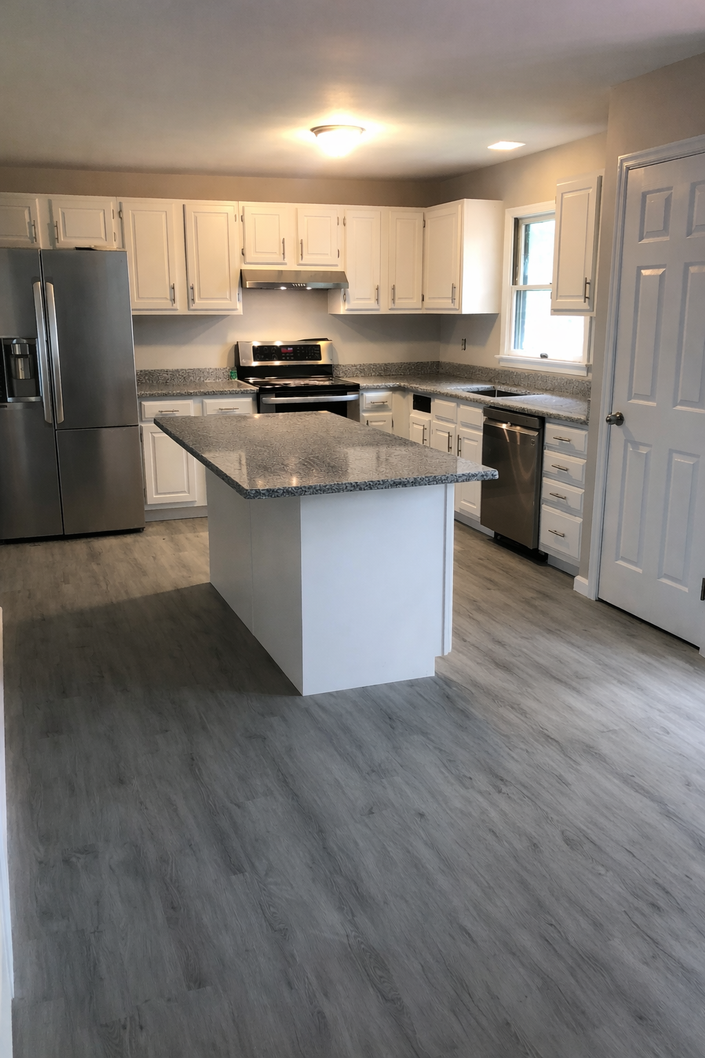 Modern kitchen remodel featuring white cabinets, a large island, granite countertops, and luxury vinyl plank flooring completed by A&A Legacy Construction. Kitchen Remodeling in Glen Mills PA